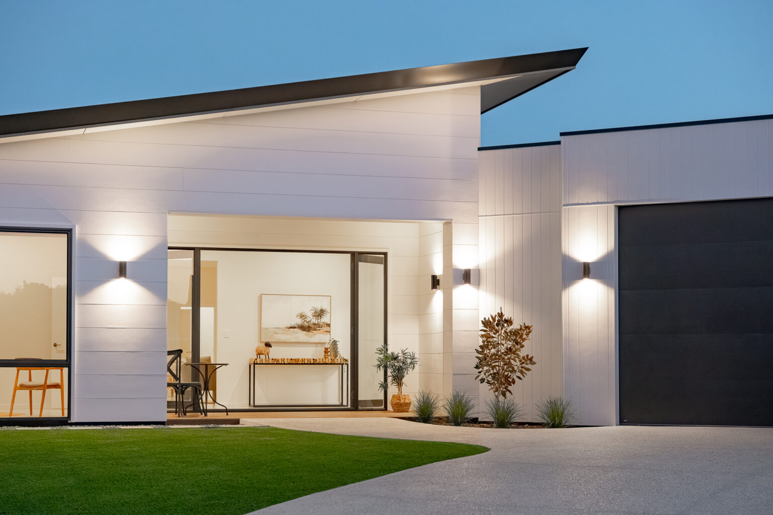 Front of a white home with a skillion roof at dusk